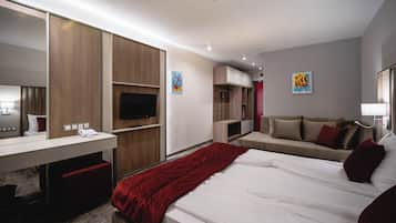 A modern hotel room with a large bed, a desk with a telephone, a TV, and a red blanket.