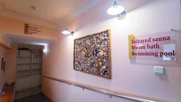 A hallway with a sign indicating an infrared sauna, steam bath, and swimming pool.