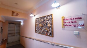 A hallway with a sign indicating an infrared sauna, steam bath, and swimming pool. - Saint George Hotel & Spa (Pomorie)