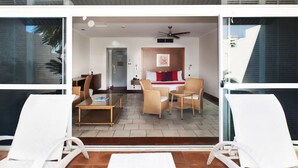 Ein modernes Hotelzimmer mit Balkon, ausgestattet mit weißen Lounge-Stühlen und einem kleinen Tisch.