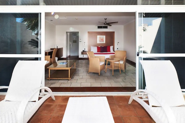 A modern hotel room with a balcony, furnished with white lounge chairs and a small table.