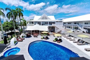 A hotel with a swimming pool, outdoor seating, and a two-story building with a white facade. - Ramada By Wyndham Cairns City Centre (Cairns)