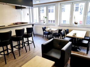 A modern restaurant with a bar area, multiple seating options including booths and tables, and large windows providing natural light. - Adler Hotel Frankfurt (Frankfurt)