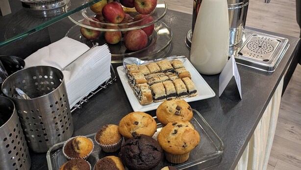 A buffet counter with various food items including fruits, muffins, and pastries.