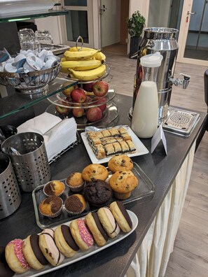 A buffet counter with various food items including fruits, muffins, and pastries. - Adler Hotel Frankfurt (Frankfurt)