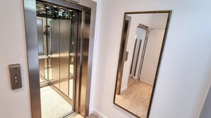 An elevator with a digital display showing the number 4, a control panel, and a mirror on the wall.