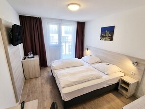 A hotel room with a bed, bedside tables, a TV, and a window with curtains. - Adler Hotel Frankfurt (Frankfurt)