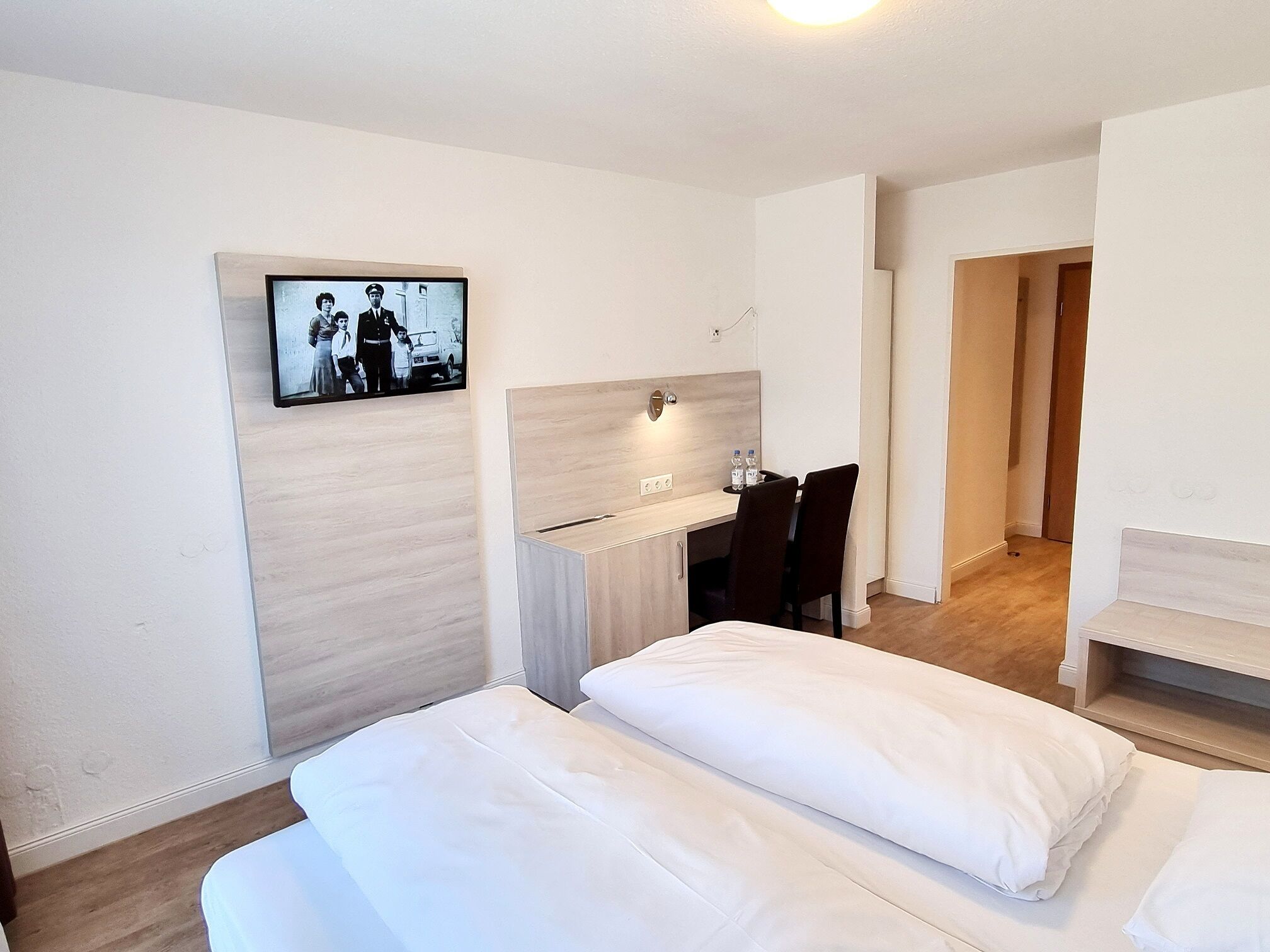 A hotel room with a bed, a desk, and a television mounted on the wall.