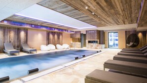 A spa area with a large pool, lounge chairs, and a wooden ceiling. - Hostellerie des Châteaux & Spa (Ottrott)