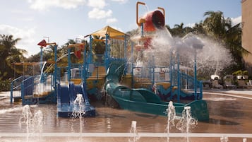 Enjoy water play structures, slides, and splash pads in a tropical setting surrounded by palm trees.