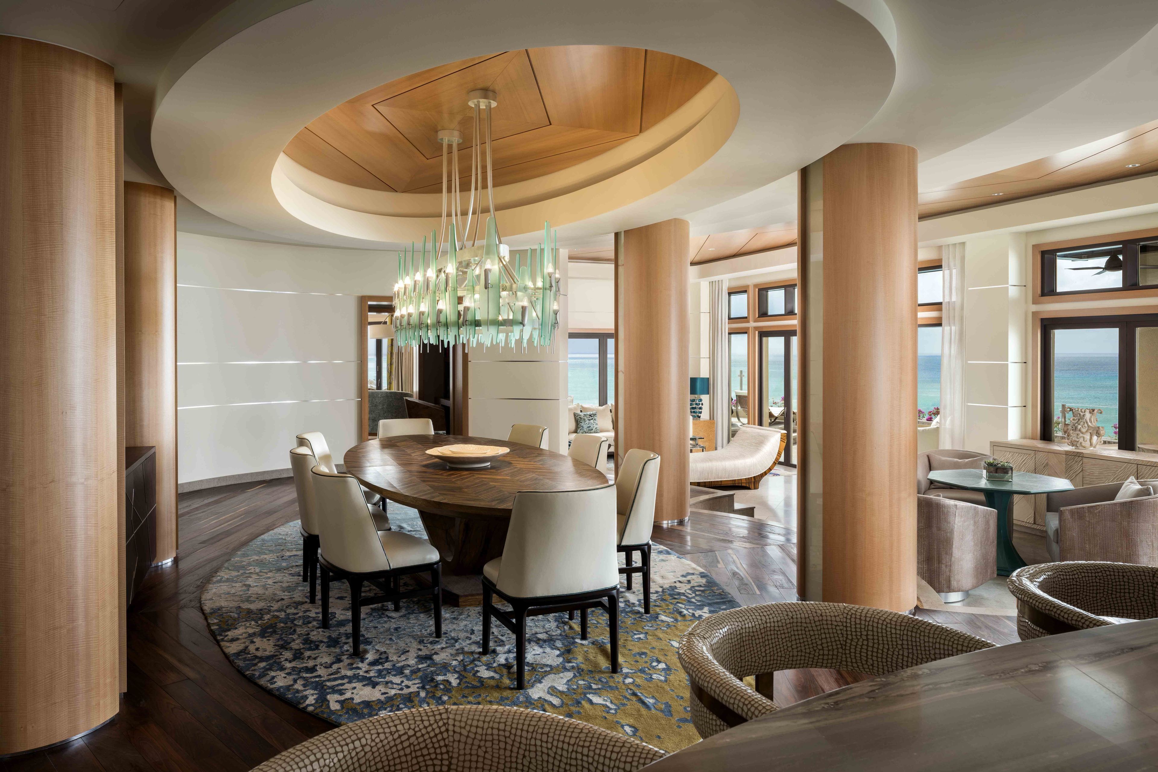 A spacious dining area with a round table, multiple chairs, and a chandelier.