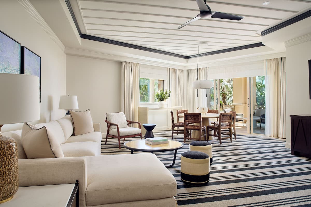 A spacious living room with a large sofa, armchairs, a coffee table, and a dining area with a table and chairs.