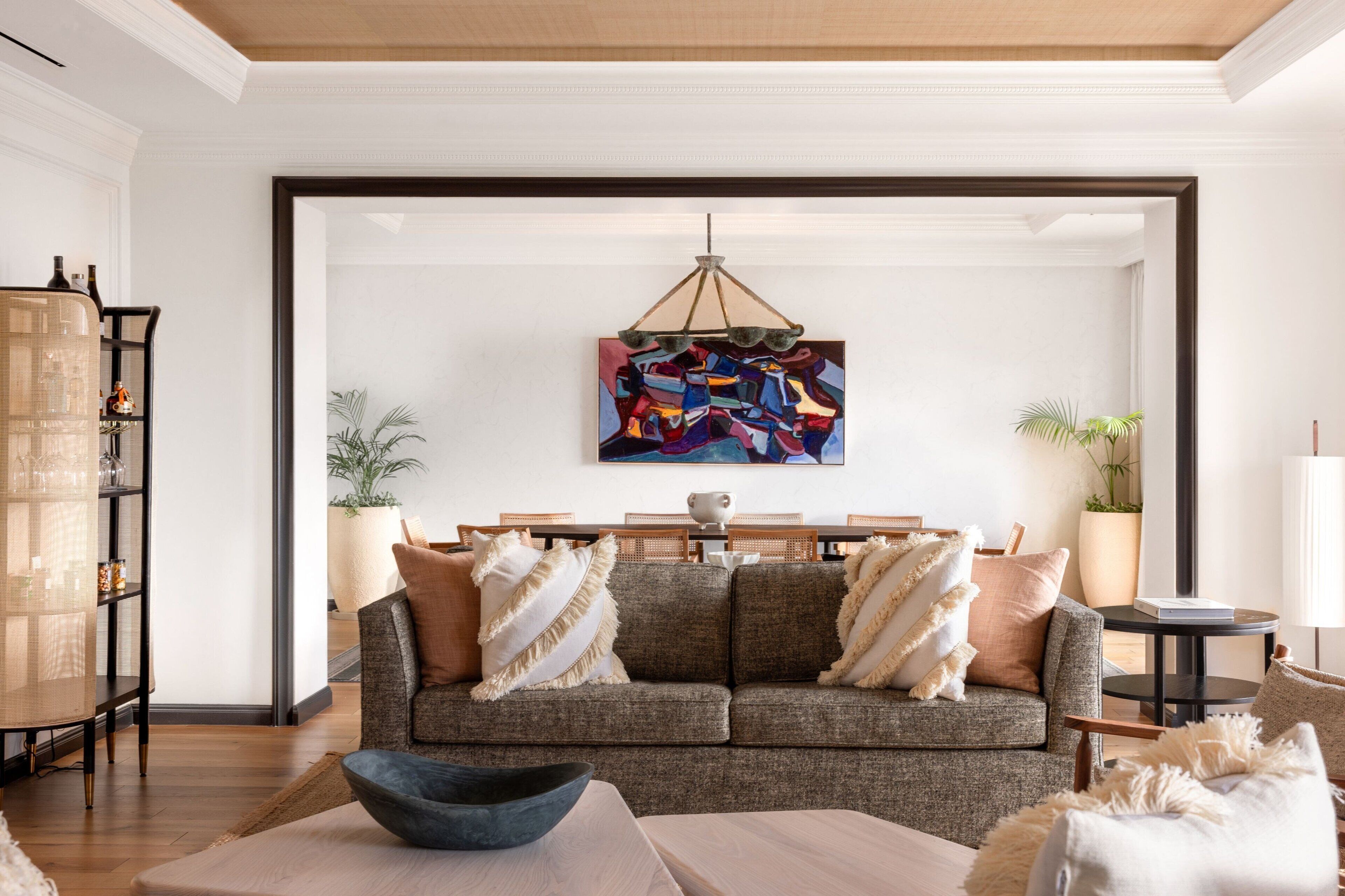 Un salón moderno con un sofá gris, una mesa de centro y un cuadro abstracto colgado.