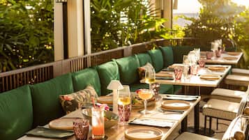A restaurant with a long dining table set for a meal, surrounded by green upholstered seating.