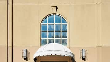 A building with a large arched window, a covered entrance, and potted plants.