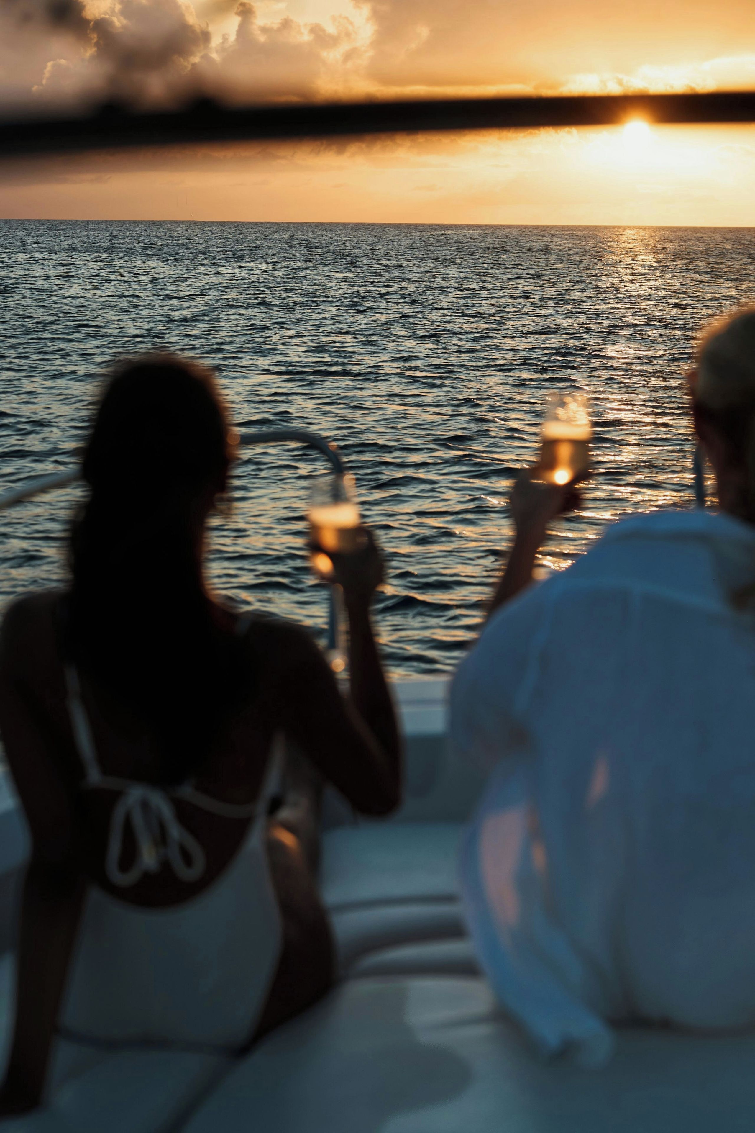 Dos personas sentadas en un bote con un atardecer de fondo.