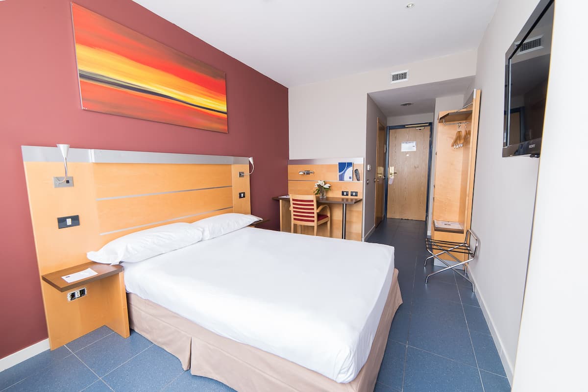 Una habitación de hotel con una cama grande, un escritorio y una silla.