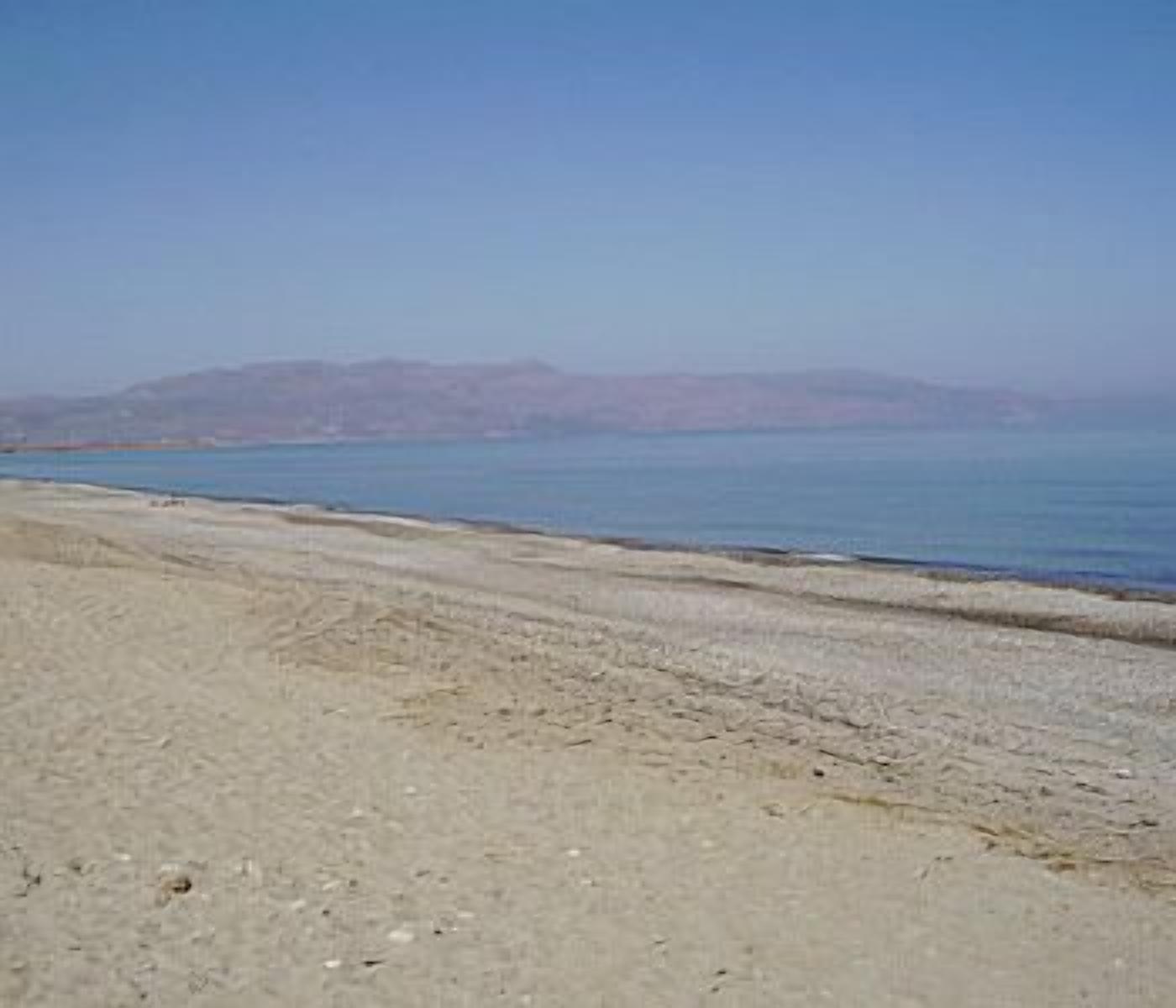 A beach with a clear view of the sea and distant mountains.