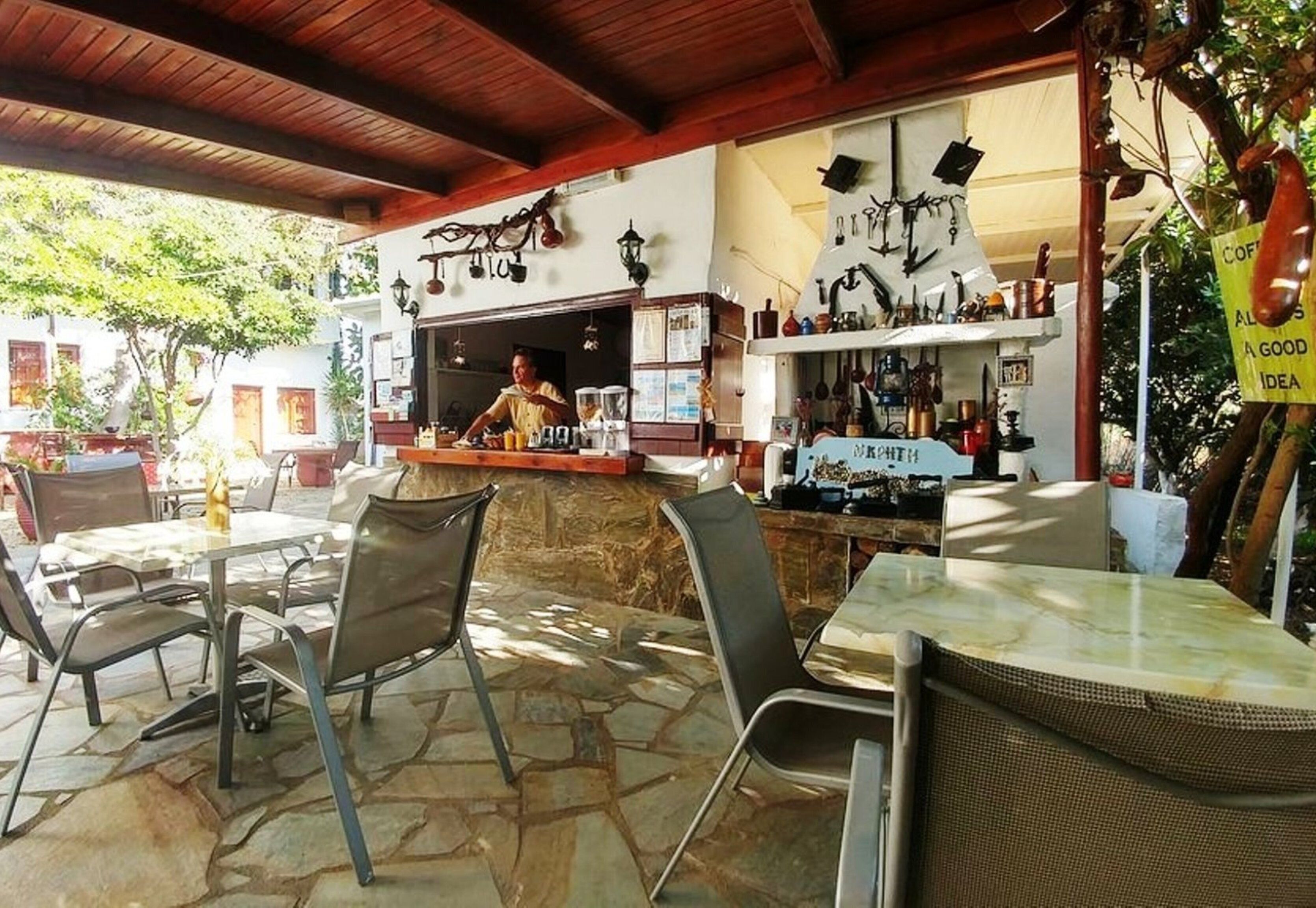 Un patio esterno con pavimento in pietra, sedie in metallo e un'area bar con una griglia.