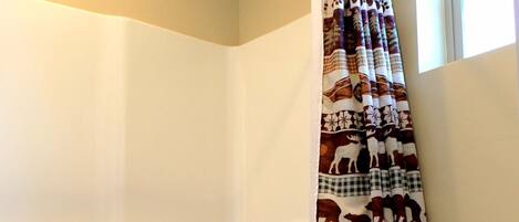 A bathroom with a bathtub, toilet, and a shower curtain with animal patterns.
