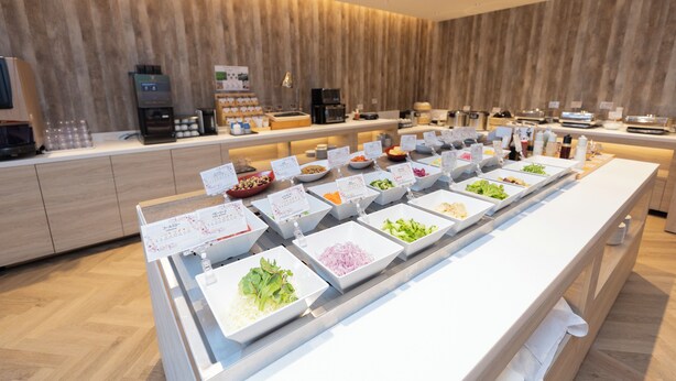 Buffet com diversos alimentos e um espaço para café.
