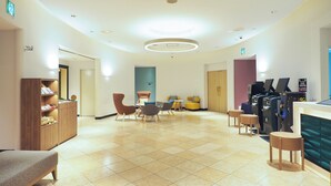 Um hall amplo com área de estar central, balcão de recepção e um suporte para roupas.