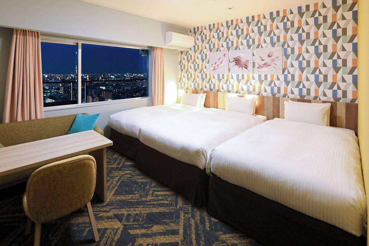 A hotel room with two beds, a desk, and a chair.