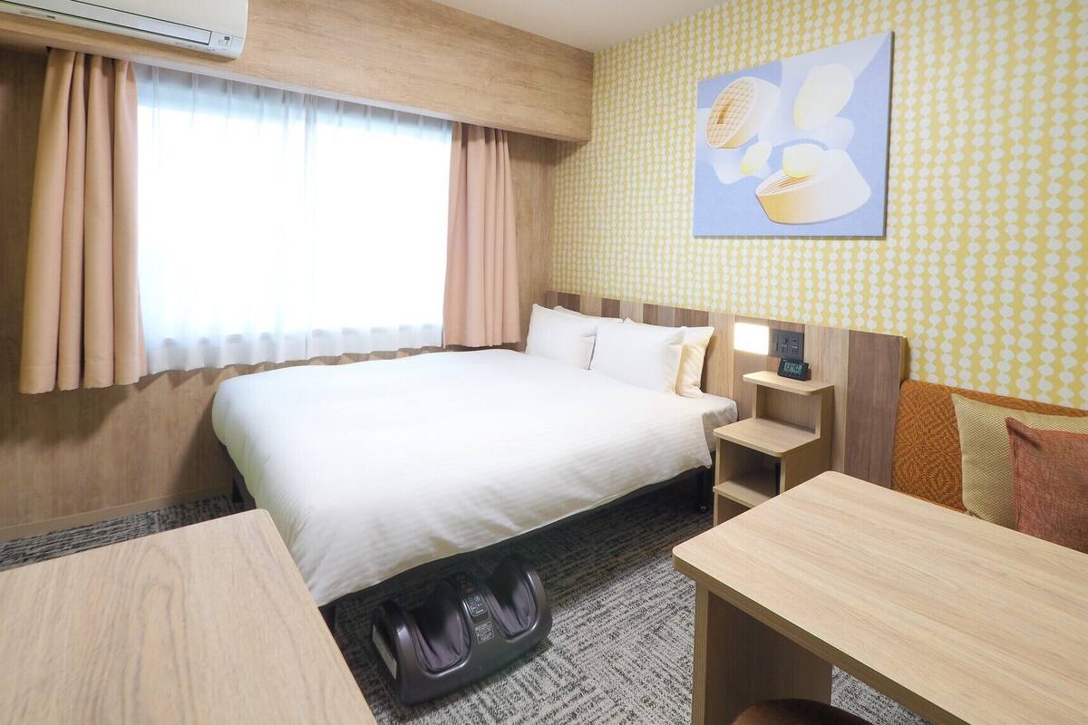 Une chambre d’hôtel équipée d’un lit, d’une table de chevet, d’une chaise et d’un climatiseur fixé au mur.
