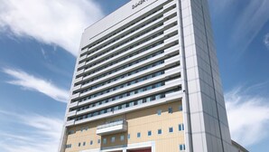 Um edifício moderno alto com várias varandas e um céu limpo ao fundo.