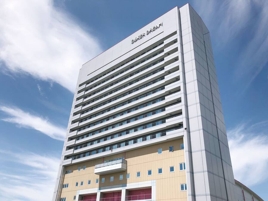 A modern high-rise building with multiple balconies and a clear sky in the background.