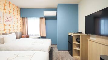 Habitación de hotel con dos camas, un escritorio, un televisor de pantalla plana, una cafetera y un aire acondicionado instalado en la pared.