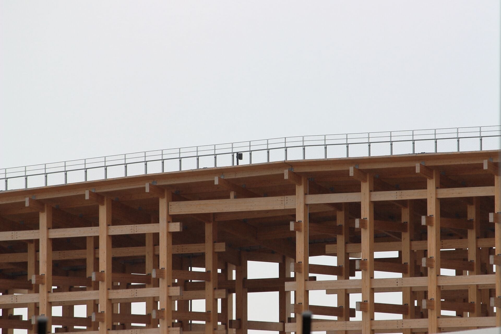 A large, multi-level wooden structure with a metal fence on top, likely a construction site.