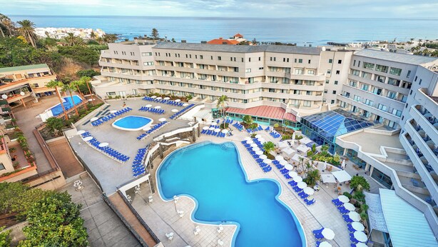 Un hotel con diverse piscine, lettini e vista sull'oceano.