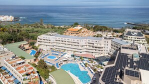 Un resort con diverse piscine, tra cui una grande piscina centrale, e vista sull'oceano.