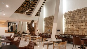 A modern interior with a stone wall, leather seating, and a variety of tables and chairs. - Vila Valverde Design Country Hotel (Lagos)