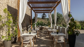 An outdoor patio with wooden pergola, white curtains, and potted plants. - Vila Valverde Design Country Hotel (Lagos)