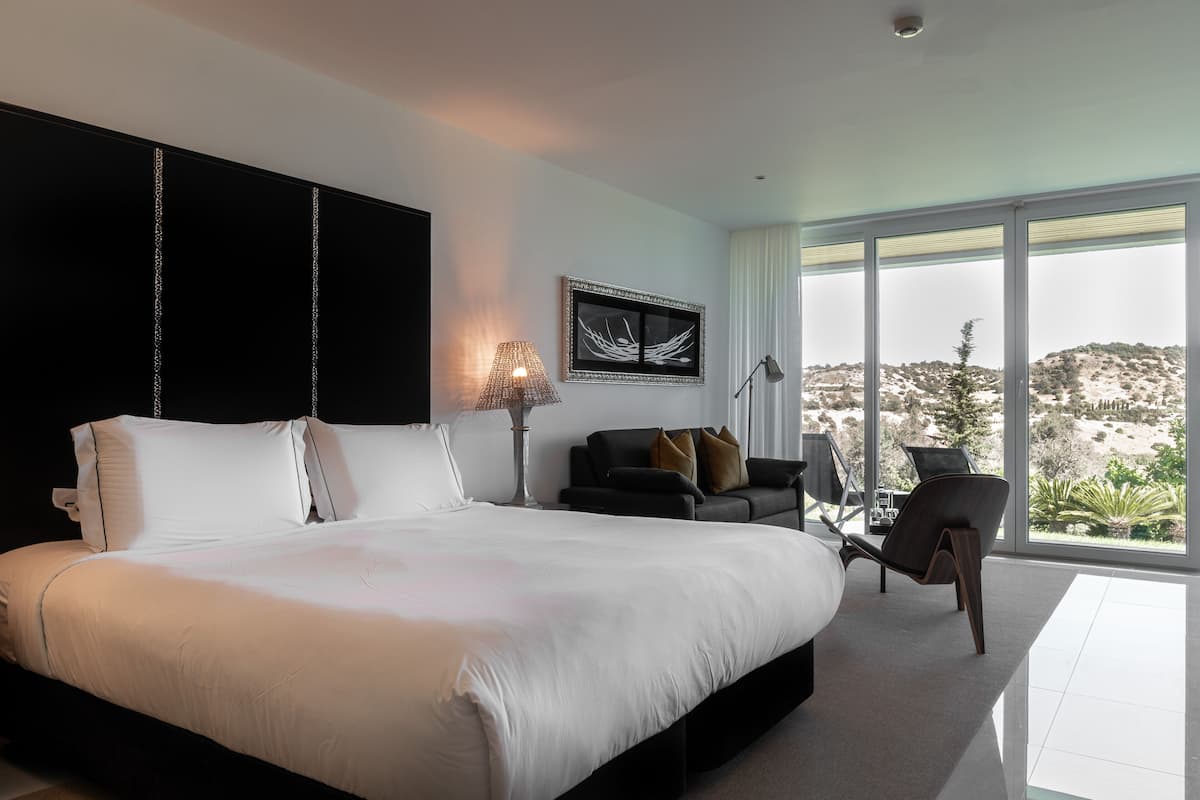 A modern bedroom with a large bed, a sofa, and a chair.