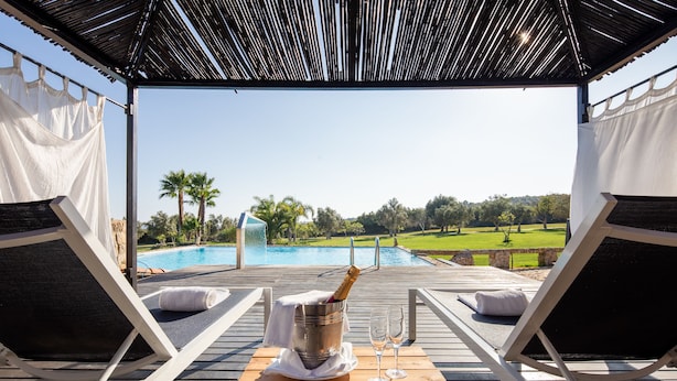 A poolside lounge with a wooden table, two lounge chairs, and a bottle of champagne. - Vila Valverde Design Country Hotel (Lagos)
