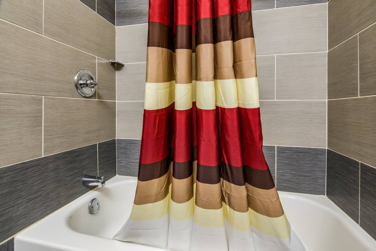 A bathroom with a bathtub, a shower curtain, and tiled walls.