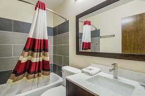 A bathroom with a bathtub, a sink, a toilet, and a mirror. - Red Roof Inn Madison Heights, VA (Madison Heights)