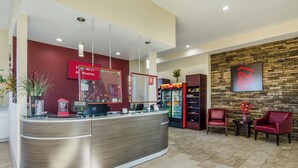 A reception area with a curved reception desk, a Coca-Cola refrigerator, and a Red Roof sign. - Red Roof Inn Madison Heights, VA (Madison Heights)