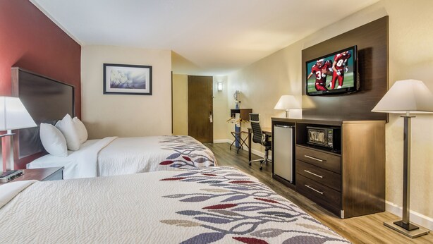 A hotel room with two beds, a desk, a television, a microwave, and a door leading to a bathroom. - Red Roof Inn Madison Heights, VA (Madison Heights)
