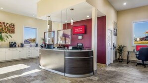 A reception desk with a digital screen advertising free Wi-Fi, a coffee machine, and a view of a cityscape through a window. - Red Roof Inn Madison Heights, VA (Madison Heights)