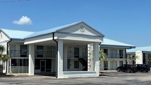 Um hotel com telhado plano, várias varandas e estacionamento.