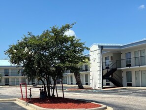 A building with a central tree, a staircase, and a parking lot. - Baymont by Wyndham Sumter Northwest (Sumter)