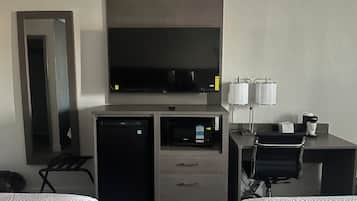 A hotel room with a bed, a desk with a computer, a television, a microwave, and a coffee maker.
