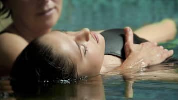 Une personne allongée dans une piscine, une autre personne se trouvant à proximité.