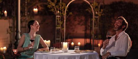 A couple dining at an outdoor table with candles and a white tablecloth.