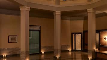 Un hall espacioso con techo alto, ventanas grandes y una lámpara central.