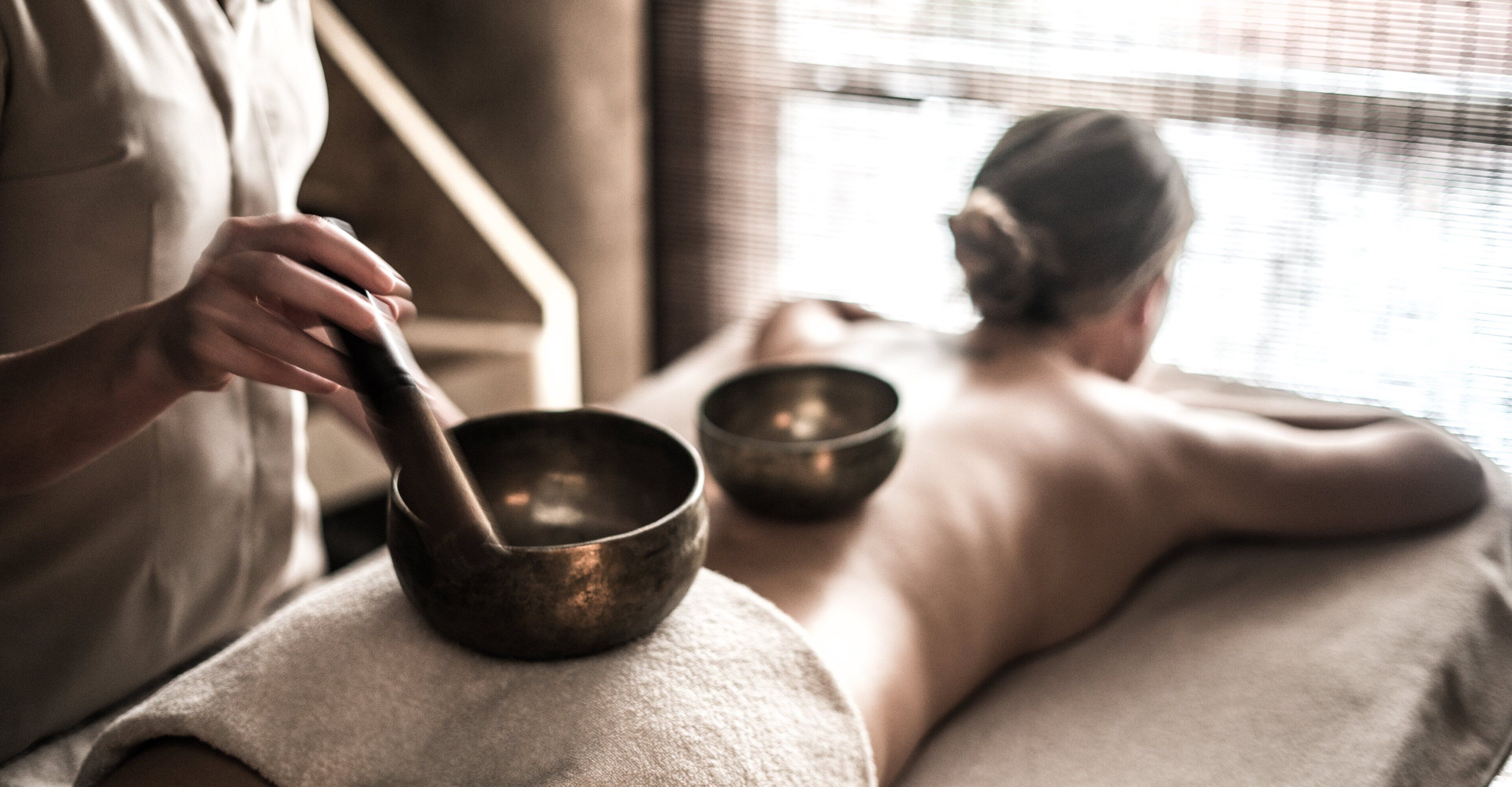 A person in a robe holding a meditation bowl, with another person in the background.